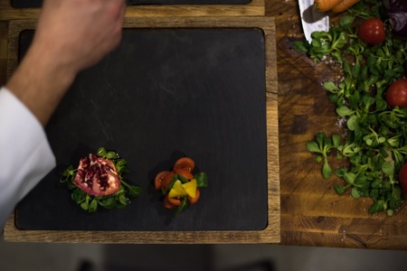 top view of Chef hands in hotel or restaurant kitchen serving beef steak with vegetable decorationの写真素材