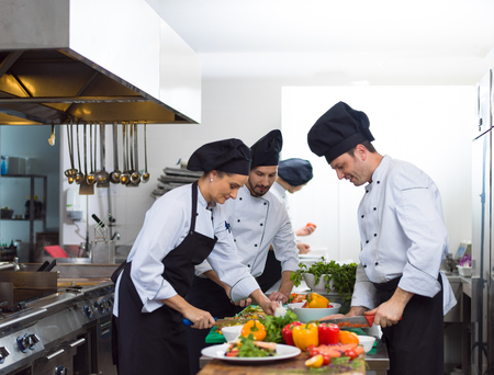 Professional team cooks and chefs preparing meals at busy hotel or restaurant  kitchen