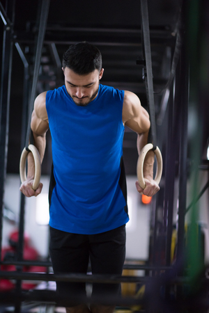 young athlete man working out pull ups with gymnastic rings at the cross fitness gymの写真素材