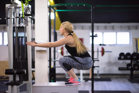 young athletic woman training  jumping on fit box at cross fitness gymの写真素材