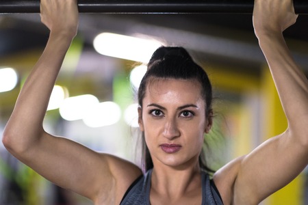 young muscular woman doing pull ups on the horizontal bar as part of Cross fitness Trainingの写真素材