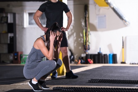 Young fit sports couple working out in functional training gym doing battle ropes cross fitness exerciseの写真素材