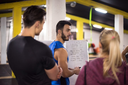 Training course.group of young athletes getting instructions from trainer before exercise at cross...