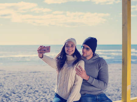 Very Happy Couple In Love Taking Selfie On The Beach in autmun dayの写真素材