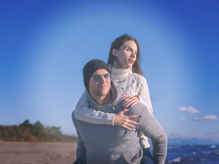 Men Giving Piggy Back Rides At Sunset By The Sea, autumn time colored filter