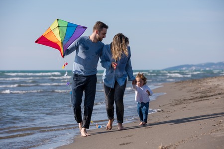 young family with kids resting and having fun with a kite at beach during autumn dayの写真素材