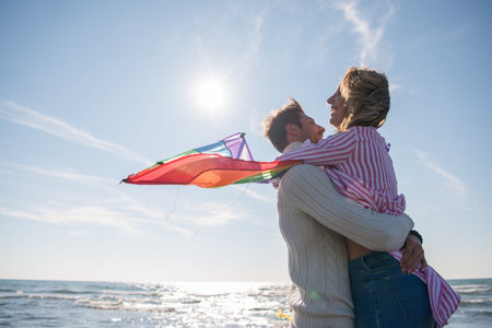 Young Couple having fun and Playing With A Kite On The Beach at autumn dayの写真素材