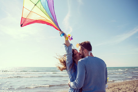 Young Couple having fun and Playing With A Kite On The Beach at autumn day filterの写真素材