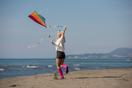 Beautiful Young Woman having fun with a kite at Beach on autumn dayの写真素材