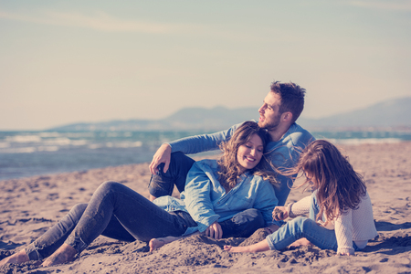 Family with kids resting and having fun at beach during autumn dayの写真素材