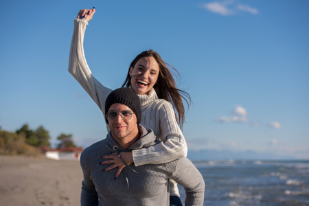 Men Giving Piggy Back Rides his girlfriend At Sunset By The Sea, autumn timeの写真素材
