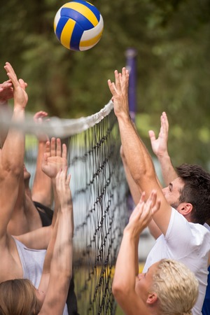 group of young friends playing Beach volleyball in a beautiful nature on the bank of the riverの写真素材