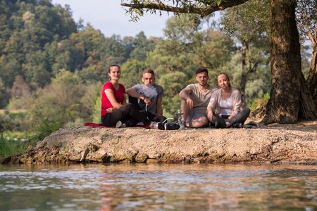 group of young friends enjoying beautiful sunny day while smoking hookah on the river bankの写真素材
