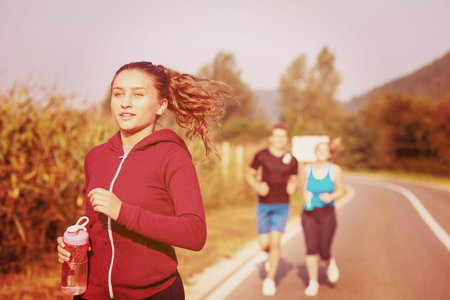group of young people jogging on country road runners running on open road on a summer day
