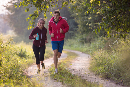 young couple enjoying in a healthy lifestyle while jogging along a country road, exercise and fitness conceptの写真素材