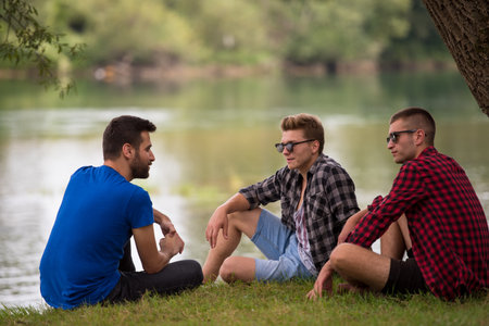 Group of young  men enjoying the nature sitting on the bank of the riverの写真素材