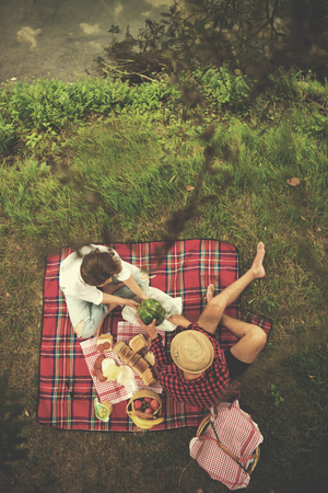 Couple in love enjoying picnic time drink and food in beautiful nature on the river bank top viewの写真素材