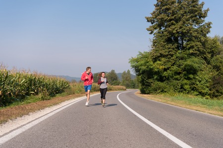 young couple enjoying in a healthy lifestyle while jogging along a country road, exercise and fitness conceptの写真素材