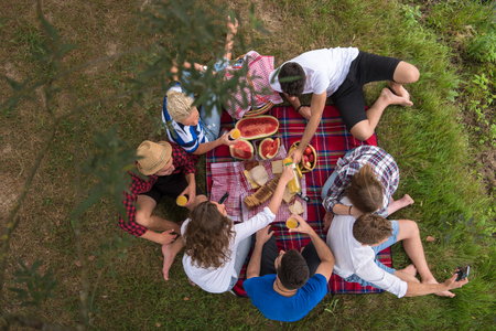 group of young friends enjoying picnic time drink and food in beautiful nature on the river bank top viewの写真素材