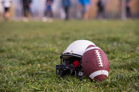 American football helmet and ball lying on fieldの写真素材