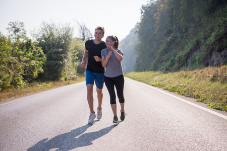 Young couple enjoying in a healthy lifestyle while jogging along a country road, exercise and fitness conceptの写真素材