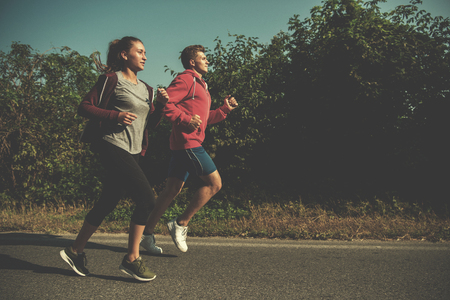 Young couple enjoying in a healthy lifestyle while jogging along a country road, exercise and fitness conceptの写真素材