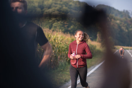 A group of young people jogging on country road runners running on open road on a summer day