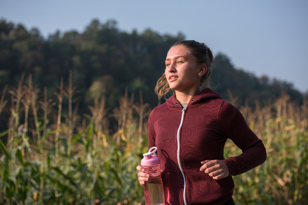 A young woman enjoying in a healthy lifestyle while jogging along a country road, exercise and fitness conceptの写真素材