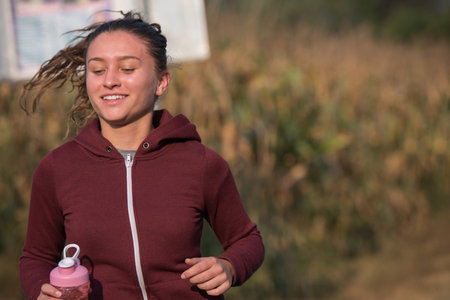 A young woman enjoying in a healthy lifestyle while jogging along a country road, exercise and...