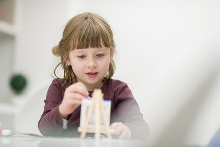 happy little girl painting on canvas image at home
