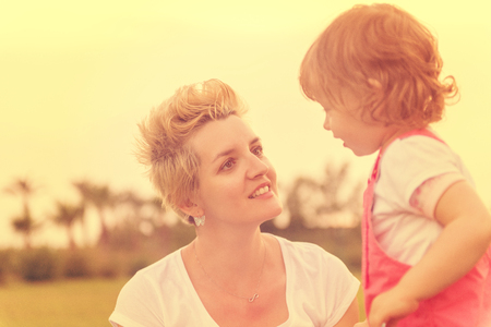 Young Mother and cute little daughter enjoying free time playing outside at backyard on the grass, happy family in nature conceptの写真素材