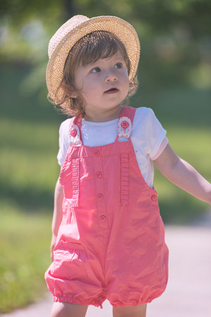 cute little girl with hat cheerfully spending time while running at Park on the summer morningの写真素材
