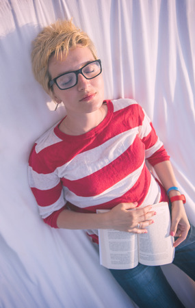 young woman reading a book while relaxing on hammock in a peaceful garden during holidayの写真素材