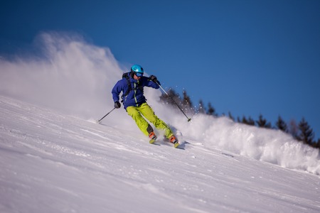 Young athlete freestyle Skier having fun while running downhill in beautiful Alpine landscape on sunny day during winter seasonの写真素材