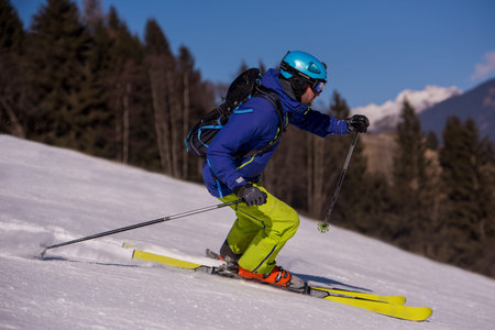 young athlete freestyle Skier having fun while running downhill in beautiful Alpine landscape on...