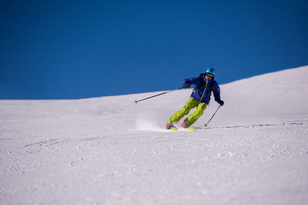 young athlete freestyle Skier having fun while running downhill in beautiful Alpine landscape on sunny day during winter seasonの写真素材