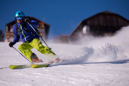 Young athlete freestyle Skier having fun while running downhill in beautiful Alpine landscape on sunny day during winter seasonの写真素材