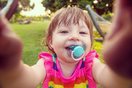 Playful cute little girl cheerfully spending time while running in the spacious backyard on the...
