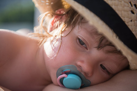 young mother and tired little daughter resting on sunbed by the pool