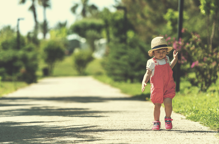 cute little girl with hat cheerfully spending time while running at Park on the summer morningの写真素材