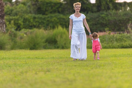 Young Mother and cute little daughter enjoying free time playing outside at backyard on the grass, happy family in nature conceptの写真素材