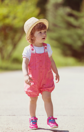 cute little girl with hat cheerfully spending time while running at Park on the summer morningの写真素材