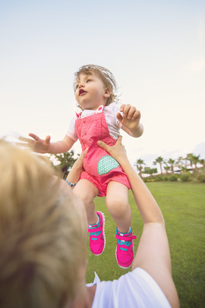 Young Mother and cute little daughter enjoying free time playing outside at backyard on the grass, happy family in nature conceptの写真素材