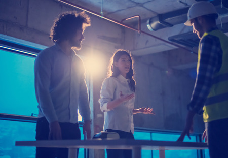 Young team of business people in group, architect and engineer on construction site checking documents and business workflow using laptop computer in new startup officeの写真素材