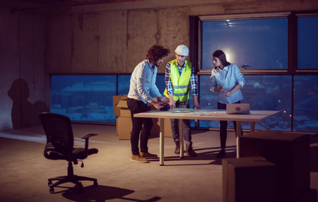 Young team of business people in group, architect and engineer on construction site checking documents and business workflow using laptop computer in new startup officeの写真素材