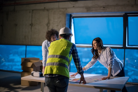 Young team of business people in group, architect and engineer on construction site checking documents and business workflow using laptop computer in new startup officeの写真素材