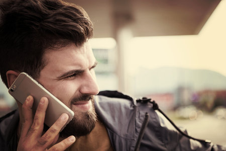 handsome young casual business man with beard using cell phone and smile outdoor on city streetの写真素材