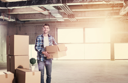 portrait of young businessman on construction site checking documents and business workflow with cardboard boxes around him in new startup officeの写真素材