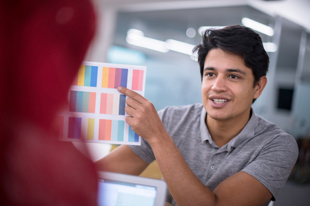 successful black muslim business woman having a meeting with her indian male colleague working on the laptop at modern startup officeの写真素材
