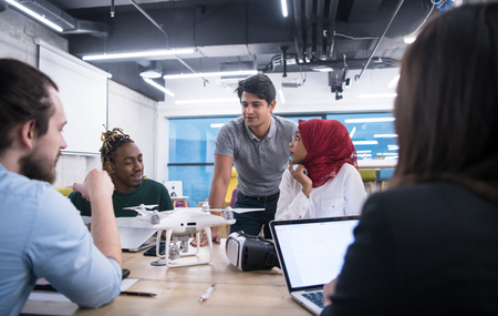 multiethnic startup business team discussing new business plan,working on laptop and tablet computer while learning about drone technology for new business advancementの写真素材